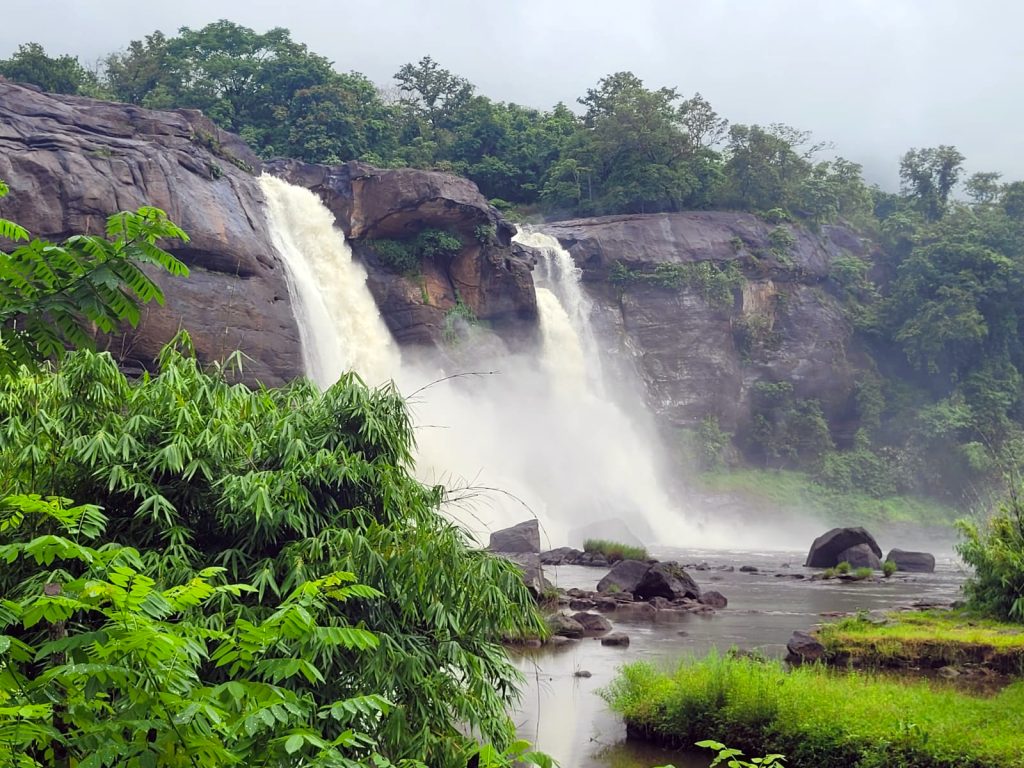Athirapally Falls in Kerala with increased monsoon water flow surrounded by lush green forests
